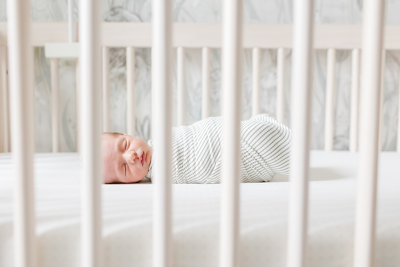 Sleeping newborn baby through crib slats | Image by Emily Gerald Photography