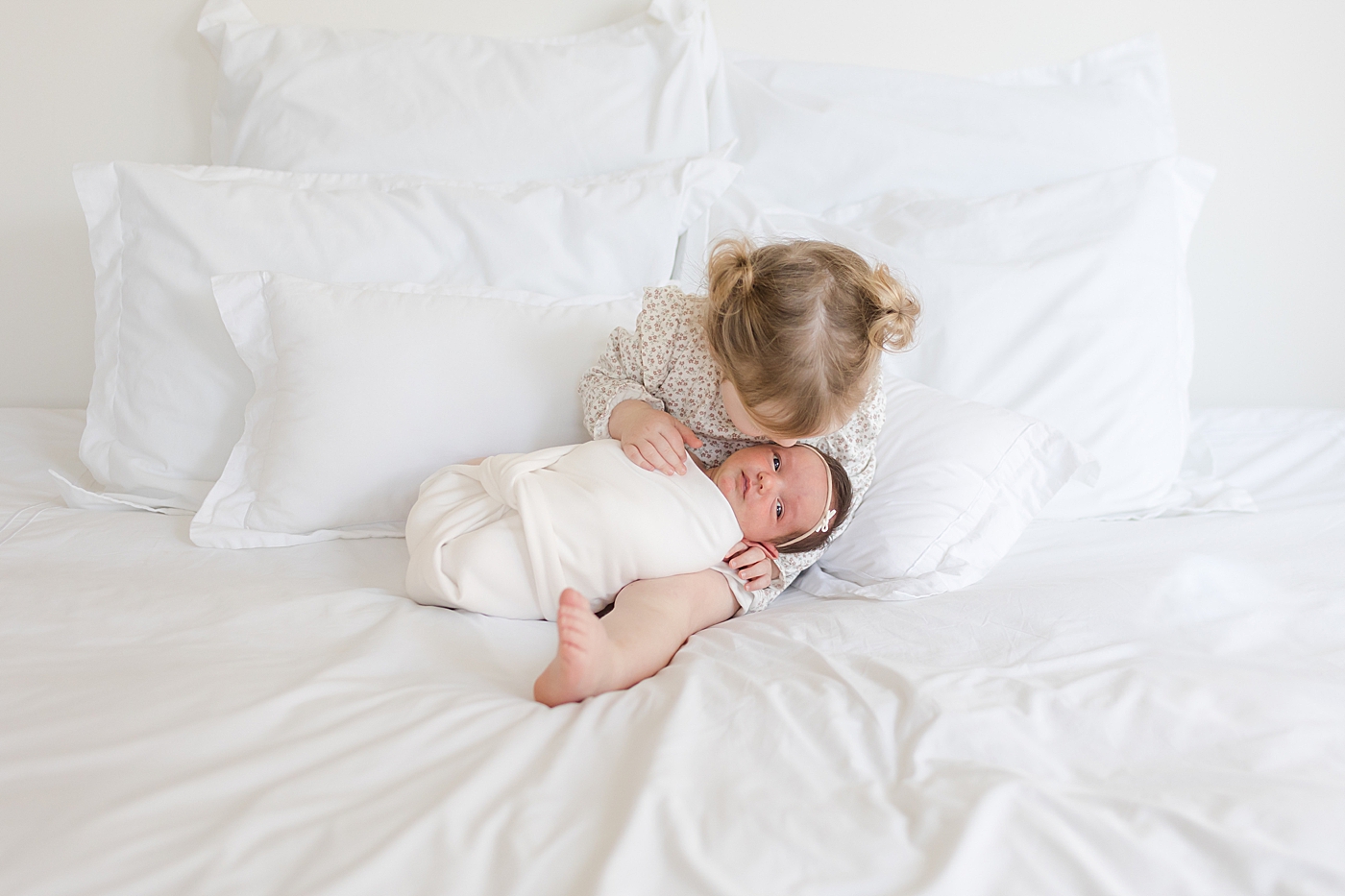 Big sister holding her newborn baby sister | Image by Emily Gerald Photography