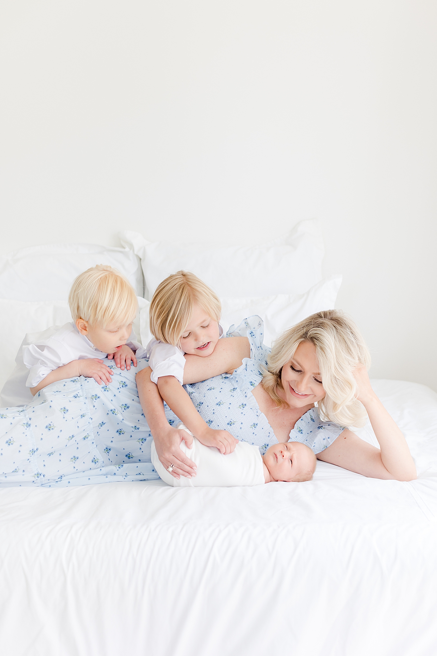 Mom with her three boys on a white bed in the studio | Image by Emily Gerald Photography