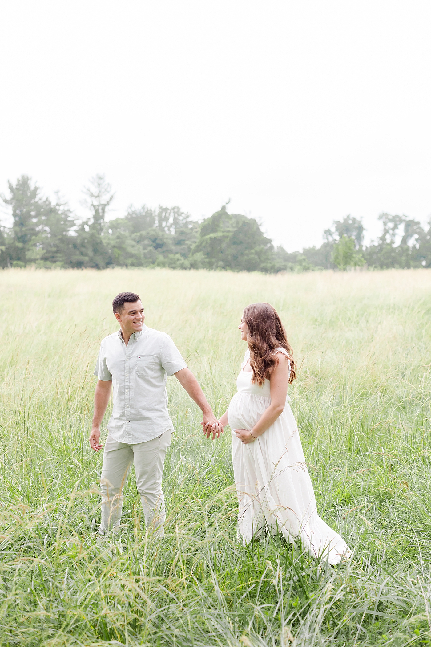 Mom and dad to be walking in a field | Image by Emily Gerald Photography