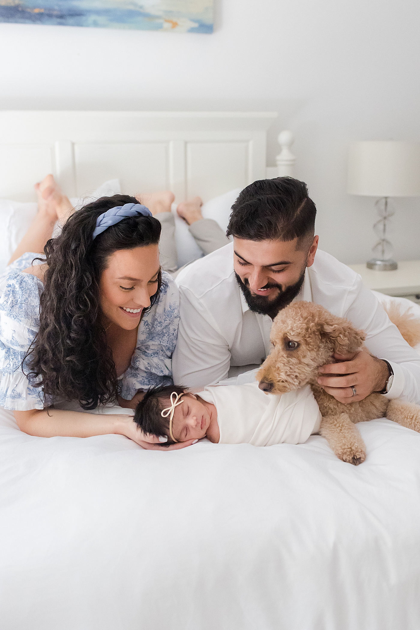 Mom and dad snuggling with their newborn baby and dog | Image by Emily Gerald