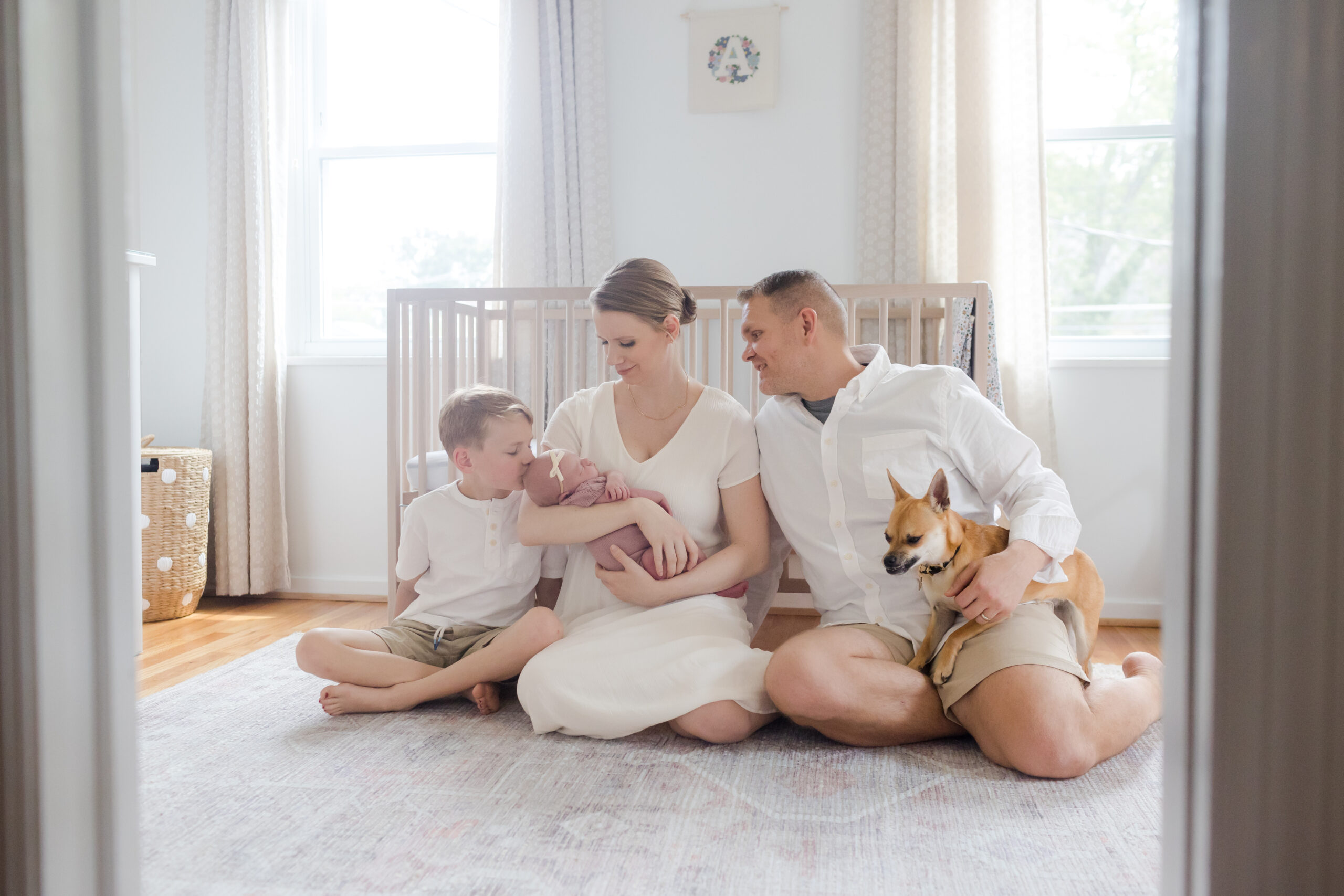 Family sitting on the floor in front of their baby's crib | Image by Emily Gerald Photography